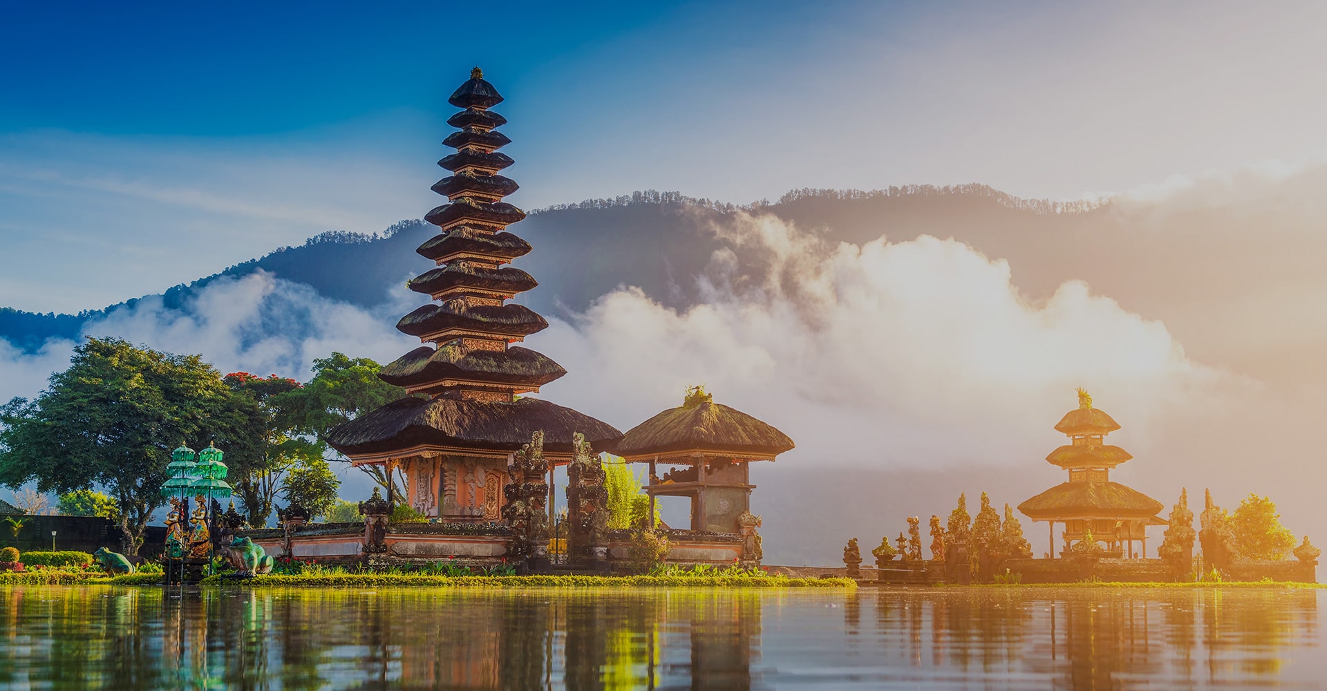 Towering Temples in Indonesia, Set Against a Backdrop of a Serene Lake and Majestic Mountains, Enveloped in Mystical Fog.